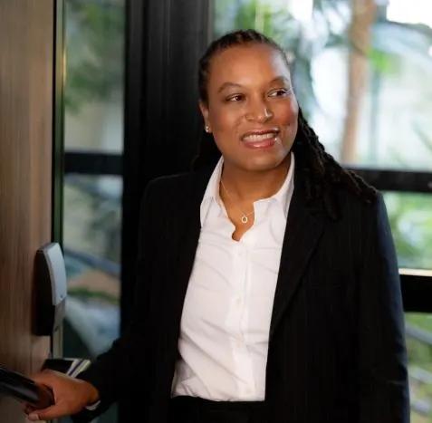 Marie-Sully Biabiany, en costume, pousse la porte vitrée d’un immeuble
