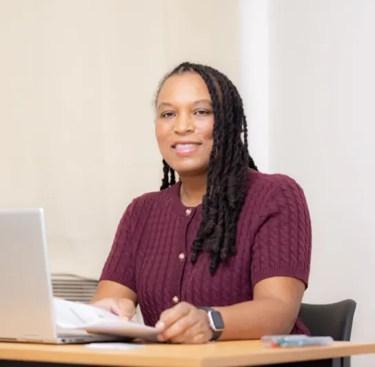 Marie-Sully Biabiany consulte des feuilles imprimées à son bureau, devant son ordinateur portable
